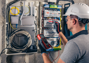 Electrician inspecting electrical panel and circuit breaker in Dubai residential building